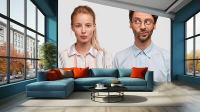 indoor shot of friendly mixed race woman and man dressed in stylish shirts, pose together against wh Wall mural