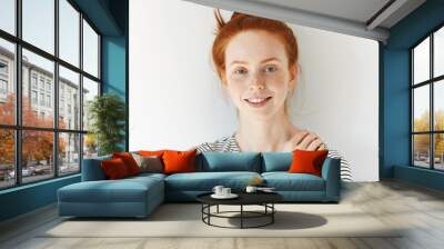 Isolated headshot of pretty teenager with perfect clean skin with freckles, wearing striped top, looking and smiling at the camera with happy and joyful expression. People and lifestyle concept Wall mural