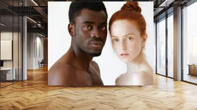 Multicultural love and relationships concept: young nude redhead freckled Caucasian woman standing next to her shirtless African boyfriend, looking at the camera with serious face expression Wall mural