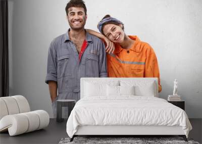 People, manual work and team work concept. Smiling joyful female and male professional workers, being glad to repair car, smile joyfully, rejoice success at work, isolated over white background Wall mural