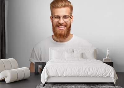 photo of attractive ginger man with satisfied expression, has thick beard, rejoices promotion at wor Wall mural