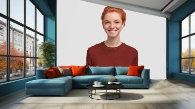 Portrait of cheerful ginger female with freckled skin, positive smile, feels relaxed and joyful, wears casual bright t shirt, poses against white background. Lovely redhead woman grins from happiness Wall mural