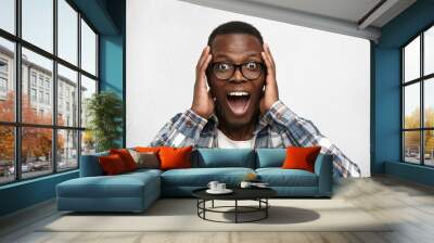 Portrait of excited young African American male screaming in shock and amazement holding hands on head. Surprised bug-eyed black hipster looking impressed, can’t believe his own luck and success Wall mural