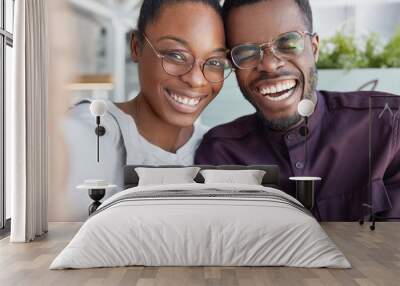 Positive dark skinned smiling woman and man have fun together, make selfie, wear glasses, laugh, happy to meet, being good friends, have good friendly relationships. Pleased African American couple Wall mural