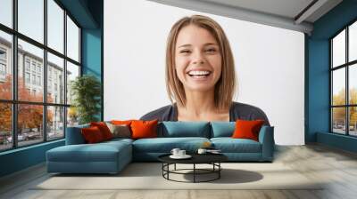 Positive human facial expressions and emotions. Cheerful attractive teenage girl with bob hairstyle grinning broadly, showing her perfect white teeth at camera while spending nice time indoors Wall mural