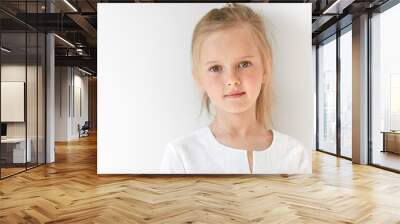 Pretty little girl with Caucasian traits looking peacefully and standing still like obedient child. She looks beautiful, attractive, nice, kind and well-mannered. Wall mural