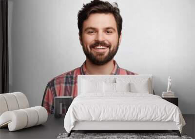 smiling bearded young male model rejoices coming weekends, dressed casually, isolated over white bac Wall mural