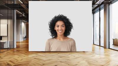 Smiling delighted young African American female has gentle smile, has white teeth, rejoices meeting with colleagues, dressed in casual clothes, isolated over white background with blank space Wall mural