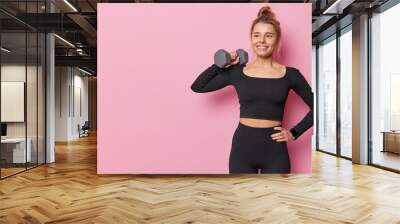 sporty fit young woman has well developed muscles by strength training raises dumbbell has training  Wall mural