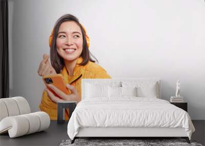 studio shot of happy asian millennial girl makes eastern like sign smiles gladfully looks away dress Wall mural