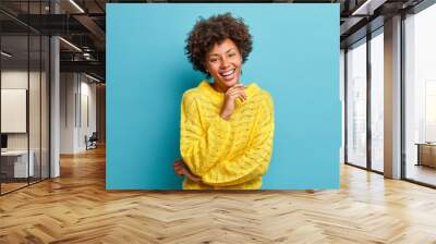 successful happy dark skinned curly woman smiles broadly with white perfect teeth and feels very gla Wall mural