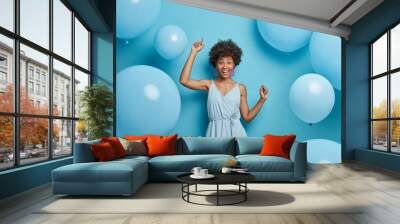 Upbeat cheerful festive woman with hollywood smile, laughs out of joy, moves carefree and dances to music, has fun, makes happy holiday photo, celebrates anniversary, surrounded by balloons. Wall mural