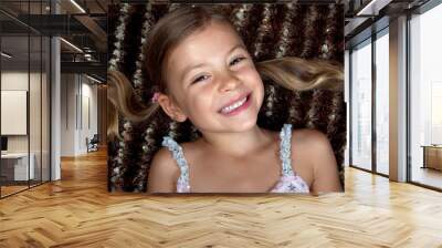 Pretty little girl lying down on a rug and smiling Wall mural