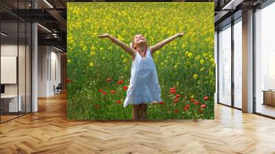 Pretty young girl surrounded by rapeseed flowers Wall mural