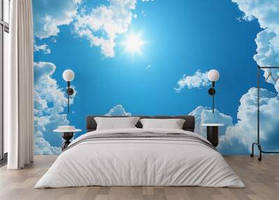 a beautiful blue sky filled with white clouds. The sun is shining brightly, casting a warm glow on the clouds. Wall mural