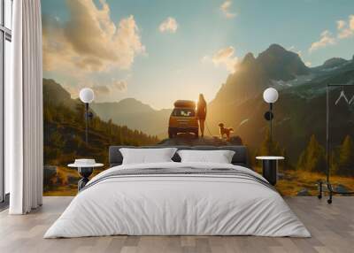 A man and woman have a road trip by a car with a dog. They look out at mountains. Wall mural