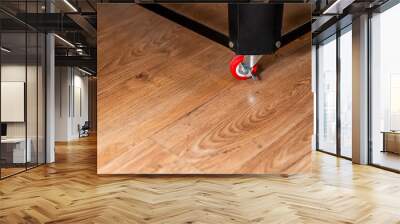 Close-Up of Table Leg with Red Wheel on Wooden Floor Wall mural