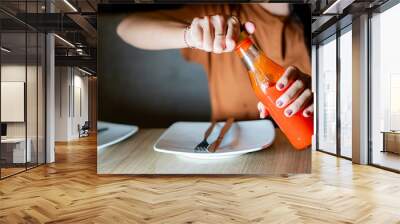 Opening a bottle of hot sauce at a dining table Wall mural