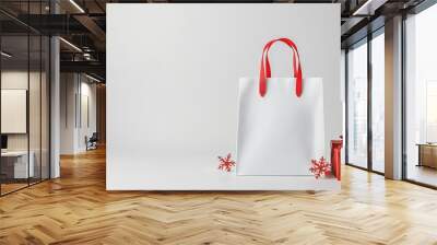 Empty Christmasthemed shopping bag, minimalist design with red ribbon handles, isolated on a white background Wall mural