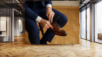 man tying shoes laces on the wooden floor Wall mural