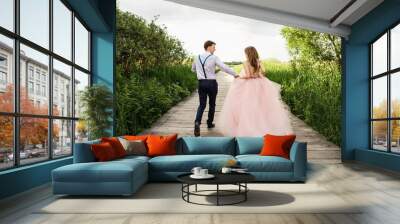 Wedding couple, happy bride and groom running on wooden bridge to place of wedding ceremony. Wedding concept Wall mural