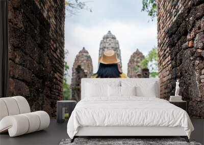 Asian tourist woman take a photo of ancient of pagoda temple thai architecture at Sukhothai,Thailand. Female traveler in casual thai cloths style visiting city concept. Wall mural