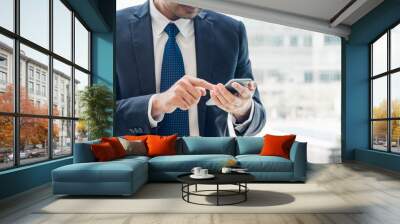 close up hand of businessman using mobile phone near office window at office building,online busines Wall mural