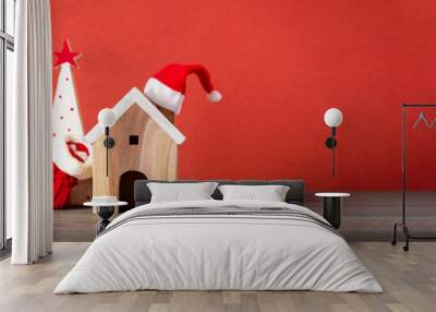 Merry chistmas and happy new year with wooden home wear santa hat on wood table with vivid red background Wall mural