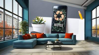 Recycle sign on green leaf on mobile app at office desk with plant and notebook.enviroment eco system concept. Wall mural