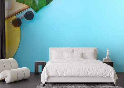 summer blue banner with yellow hat ,sunglasses,seashell,frame and monstera leaf on blue background top view. Wall mural