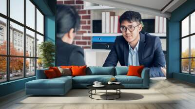 young asian businessman and businesswoman talking about business agreement at meeting table in modern office.business partnership concept.satisfied the deal with client negotiation Wall mural