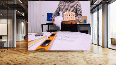 Close-up hand of male Architect drawing blueprint on work space in construction site. Wall mural