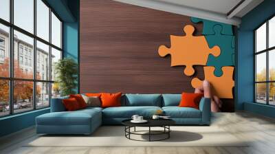 Hands assembling colorful puzzle pieces on a wooden surface, representing teamwork and problem-solving. Wall mural