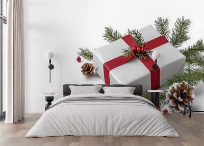 A beautifully wrapped Christmas gift decorated with red ribbon and pine branches on a white background. Wall mural