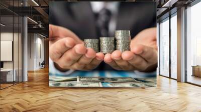 Business professional holding stacks of coins representing financial growth and investment opportunities, with dollar bills in the foreground. Wall mural