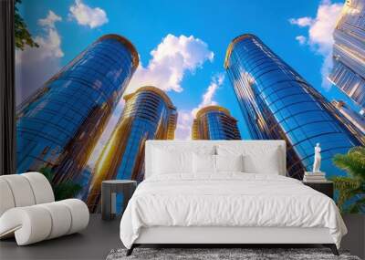 Stunning urban skyline featuring modern glass skyscrapers under a bright blue sky with fluffy clouds and sunlight. Wall mural