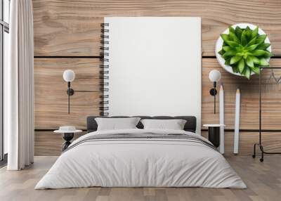 Top view of a blank spiral notebook with two pencils and a potted succulent plant on a wooden desk background. Wall mural