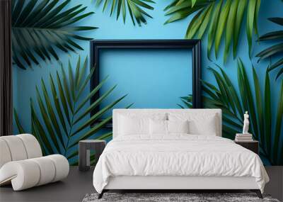 photo of a black picture frame on a light blue background with palm leaves, in a flat lay top view Wall mural