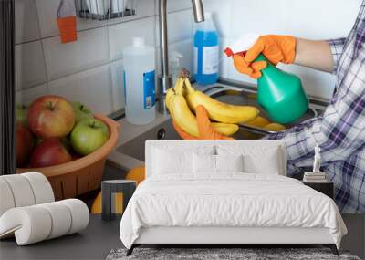 Spraying disinfecting chemical on the fruit in the kitchen. COVID-19 Coronavirus pandemic concept. Wall mural