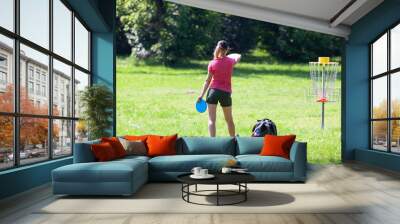 Young woman playing flying disc golf sport game in the city park or nature Wall mural