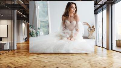 Attractive girl in a beige dress poses in the studio loft Wall mural