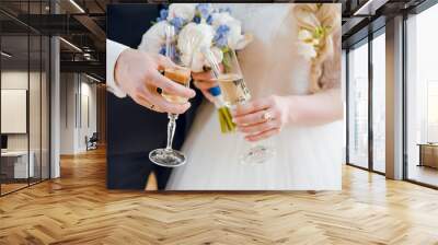 The bride and groom hold glasses of champagne in their hands on wedding celebration. Close up. Wedding ceremony. Wall mural