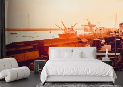 Silhouette of heavy crane tool in ship port and contain stock at sunset scene Wall mural