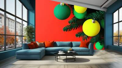 A festive arrangement featuring green and yellow Christmas ornaments hanging from a green branch against a vibrant red backdrop, ideal for joyful holiday settings. Wall mural