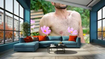 handsome shirtless man with beard sitting outside in garden Wall mural