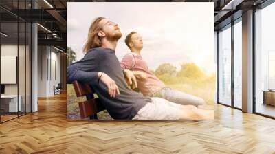 two young men sitting on bench and enjoying the sun Wall mural