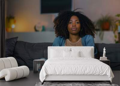 young black woman sitting on sofa and looking depressed Wall mural