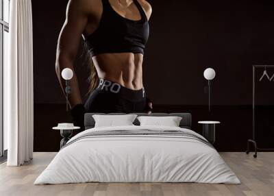 Close up athletic woman with abs on black background. Young female bodybuilder with strong abdominal muscles posing. Wall mural