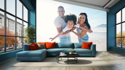 Beach, portrait and parents flying their kid on the sand by the ocean on a family vacation. Happy, smile and girl child playing and bonding with her young mother and father on tropical summer holiday Wall mural