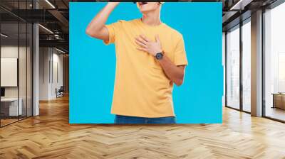 Phone, headphones and man singing in studio listening to music, radio or playlist for entertainment. Smile, technology and male person streaming song or album for karaoke isolated by blue background. Wall mural